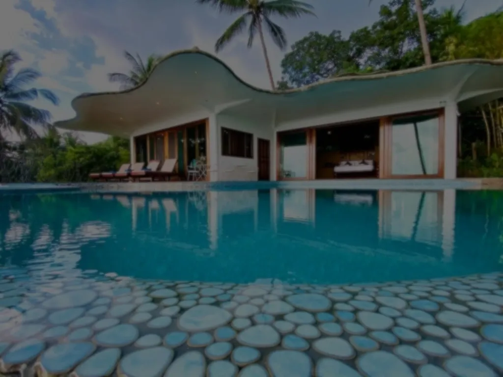 Exterior of the Orchid Luxury Villa in Koh Tao featuring 3 bedrooms and 2 bathrooms. The image shows the award-winning infinity pool overlooking the ocean, surrounded by lush jungle greenery.